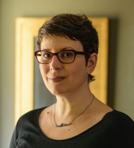 Photo of author standing in front of a gold framed mirror.